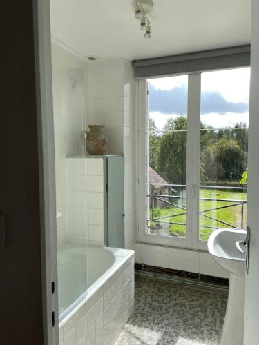 une salle de bain avec une baignoire et une fenêtre dans l'établissement Le Presbytère, maison de campagne familiale, à La Poterie-au-Perche
