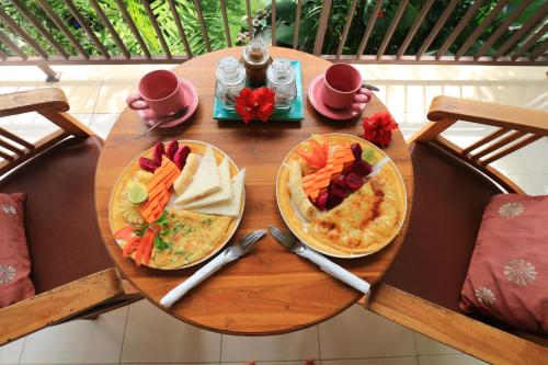een houten tafel met twee borden eten erop bij Frangipani Bungalow in Ubud