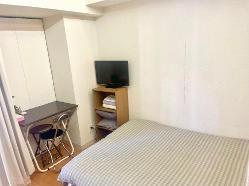 a bedroom with a bed and a desk and a television at Shinjuku West Park Inn Hanabi House in Tokyo