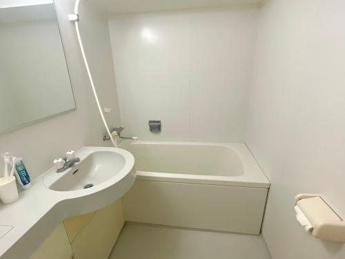 a white bathroom with a sink and a bath tub at Shinjuku West Park Inn Hanabi House in Tokyo
