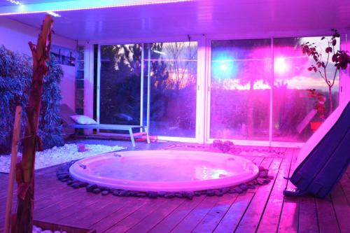 LOVEROOM avec JACCUZI Villa Les Pins في Marolles: حوض جاكوزي في غرفة ذات أضواء وردية