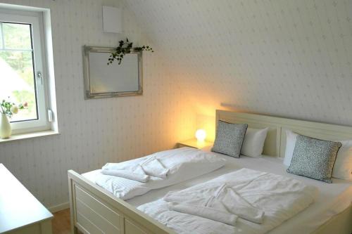Una cama blanca en un dormitorio con ventana. en Kleine Birke, en Zirchow