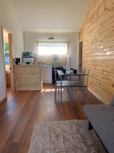Una sala de estar con mesa y sillas y una cocina. en Cabañas Apatere, en Llanquihue