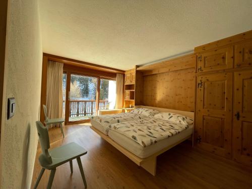 a bedroom with a bed and a chair and a window at Chesa La Furia in Pontresina