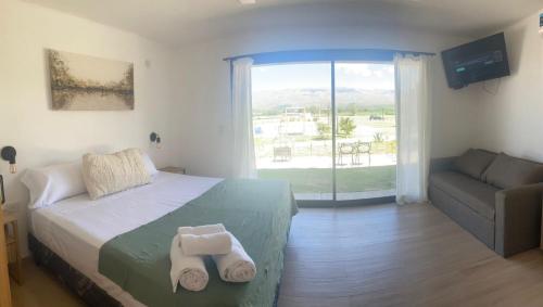 a bedroom with a bed and a couch and a window at Casa Luoni Hotel Boutique & Aparts in San Luis