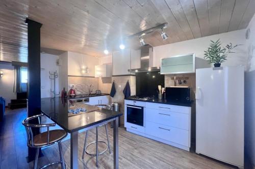 - une cuisine avec des placards blancs, une table et un réfrigérateur dans l'établissement Casa Montcalm - T2 -Clim -Proche GareCentre Brive, à Brive-la-Gaillarde