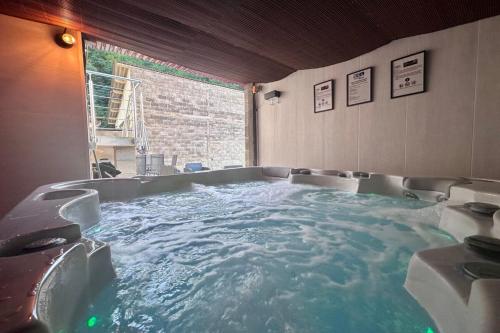 una grande vasca idromassaggio in una stanza con acqua di Villa Platon - Jaccuzi - JardinTerrassePétanque a Brive-la-Gaillarde