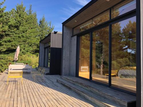 a wooden deck with a house with glass windows at Casa Puertecillo in Puertecillo