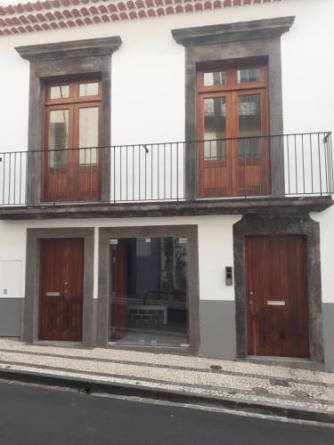 a white building with wooden doors and a balcony at Ferreiros 184 in Funchal