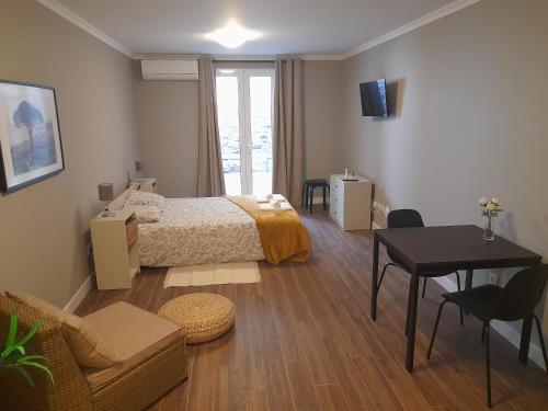 a bedroom with a bed and a table and a desk at Ferreiros 184 in Funchal