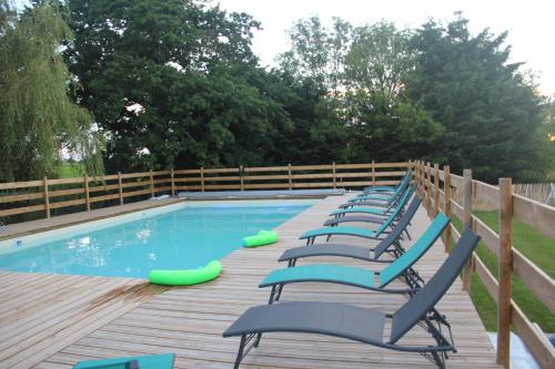 a row of chairs sitting on a deck next to a swimming pool at LOGIS DU GRAND PIN in Saint-Martin-des-Entrées