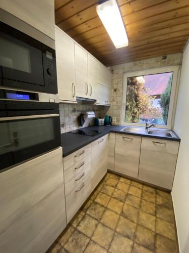 a kitchen with white cabinets and a sink and a window at Wutachtal 12 in Blumberg