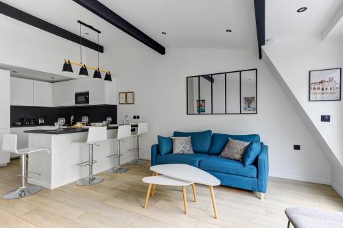 ein Wohnzimmer mit einer blauen Couch und einer Küche in der Unterkunft Suite New Delhi - Superbe Appartement in Suresnes