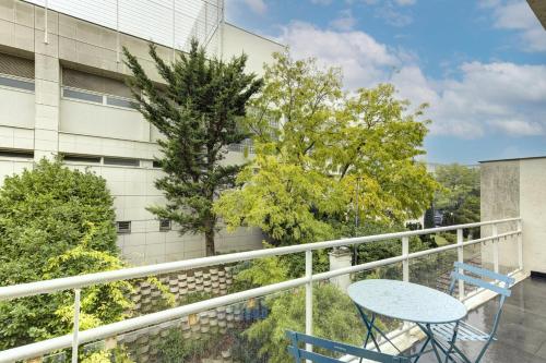 ein Balkon mit Tisch und Stühlen und ein Gebäude in der Unterkunft Suite New Delhi - Superbe Appartement in Suresnes
