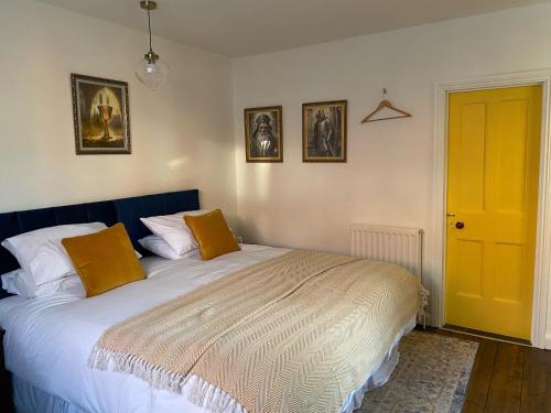 a bedroom with a bed with orange pillows and a yellow door at Grail Cottage in Glastonbury
