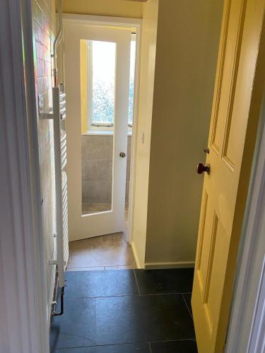 a hallway with a door leading to a bathroom at Grail Cottage in Glastonbury