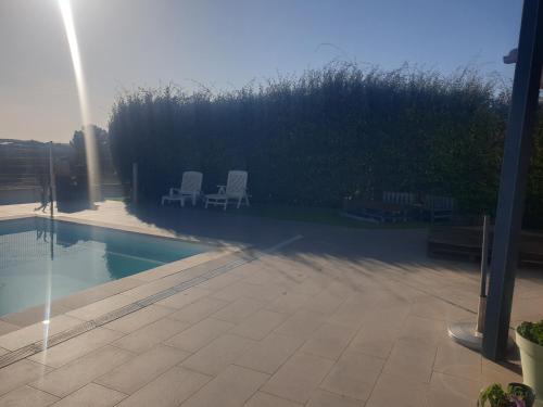 two white chairs sitting next to a swimming pool at Chambre d'hôte avec accès piscine in Gigean