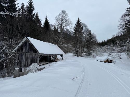 a barn covered in snow next to a road at Romantikapartment mit Sommercard in Ramsau am Dachstein