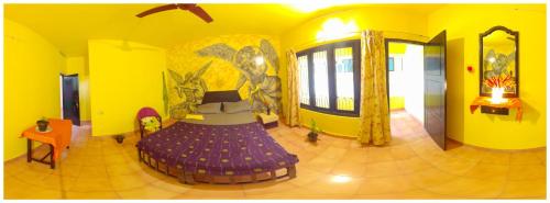 a room with a purple bed in a yellow room at Santa Maria Hostel Kovalam in Kovalam