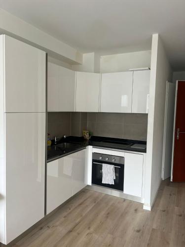 a kitchen with white cabinets and a stove top oven at Appartement Famille in Geneva