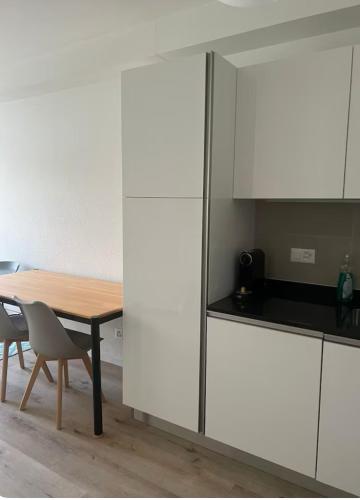 a kitchen with white cabinets and a wooden table at Appartement Famille in Geneva