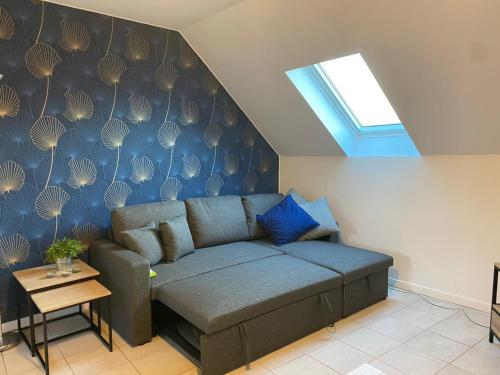 - un canapé dans le salon orné d'un mur bleu dans l'établissement Le Nid de Liais, à Cherbourg en Cotentin