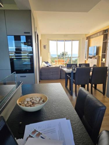 - une cuisine et un salon avec une table et un bol de nourriture dans l'établissement Résidence Le Château - Parc Santa Lucia, à Saint-Raphaël