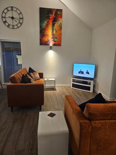 a living room with two couches and a flat screen tv at Brooke View Barns No2 in Norwich