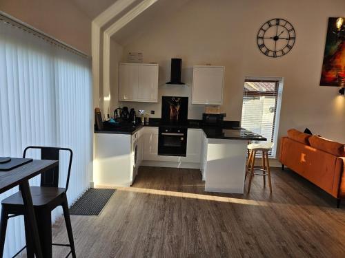 a kitchen with white cabinets and a table and chairs at Brooke View Barns No2 in Norwich