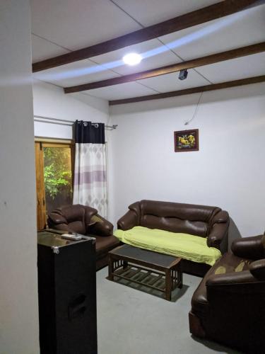 a living room with leather furniture and a couch at Mahi's Place in Minneriya