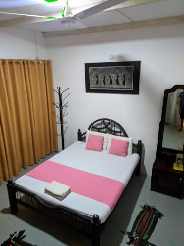 a bedroom with a bed with pink and white sheets at Mahi's Place in Minneriya