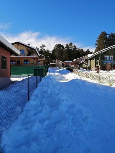 a snow covered street with a fence and houses at Къща за гости Дар in Batak