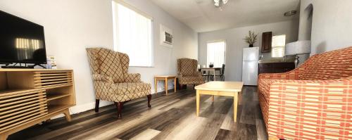 a living room with a couch and a tv and chairs at Johns Pass Beach Motel in St Pete Beach