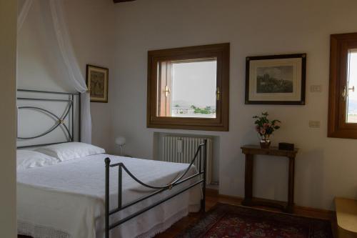 a bedroom with a bed and two windows at Palazzetto Ardi in Torri di Confine