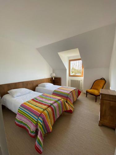 une chambre d'hôtel avec deux lits et une chaise dans l'établissement Gîte de La Dure, à Salignac Eyvigues