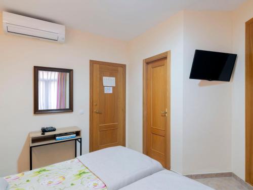 a bedroom with a bed and a tv on the wall at Hostal Antigua Morellana in Valencia