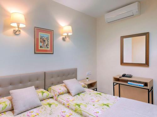 a bedroom with a bed with two pillows and a mirror at Hostal Antigua Morellana in Valencia