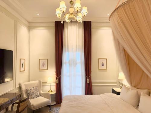 a bedroom with a bed and a chair and a chandelier at The Atlantic Langkawi in Pantai Cenang