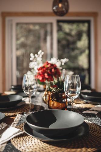 a table with black plates and wine glasses on it at Villa Experience Nature Le Nid in Saint-Irénée