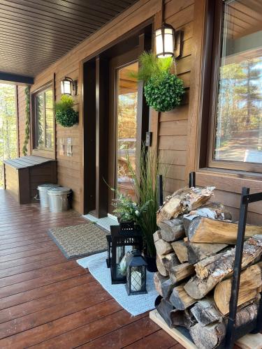 a porch of a house with a stack of logs at Villa Experience Nature Le Nid in Saint-Irénée