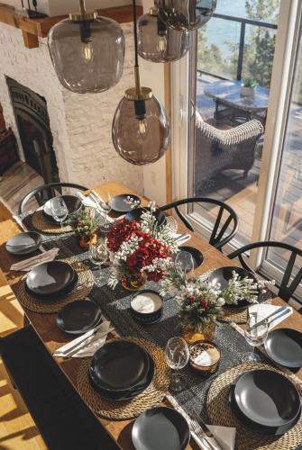 a wooden table with black plates and flowers on it at Villa Experience Nature Le Nid in Saint-Irénée
