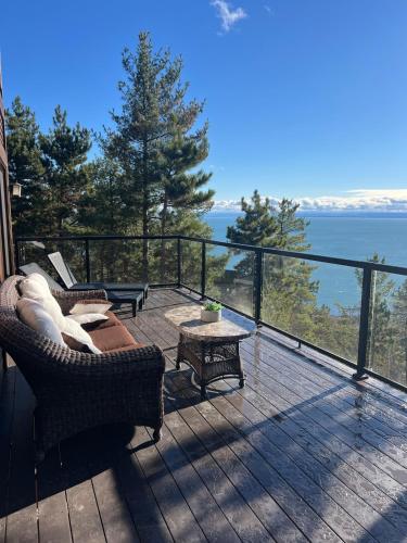 a deck with a view of the water from a house at Villa Experience Nature Le Nid in Saint-Irénée
