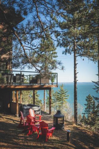 a group of red chairs and a grill and the ocean at Villa Experience Nature Le Nid in Saint-Irénée