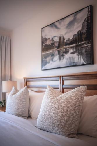 a bed with white pillows and a painting on the wall at Villa Experience Nature Le Nid in Saint-Irénée