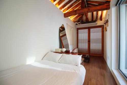 a bedroom with a white bed and a large window at Cheongryang-Anchae 2BR 2BA Hanok Spa Free Parking in Seoul