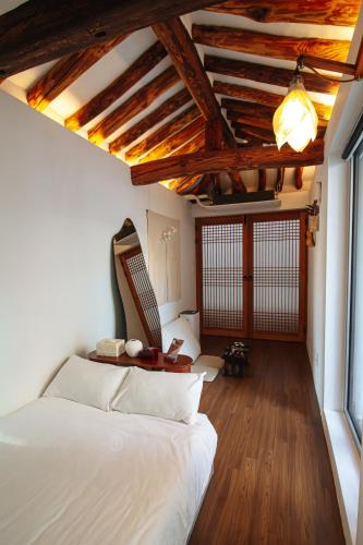 a bedroom with a white bed and a wooden ceiling at Cheongryang-Anchae 2BR 2BA Hanok Spa Free Parking in Seoul
