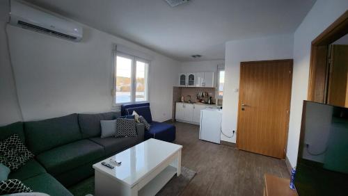 a living room with a green couch and a kitchen at Kuća sa lepim pogledom - porodica Čolović in Rudno