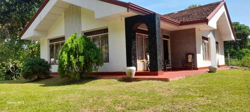 a small house with a green lawn in front of it at Family Villa Talalla in Talalla