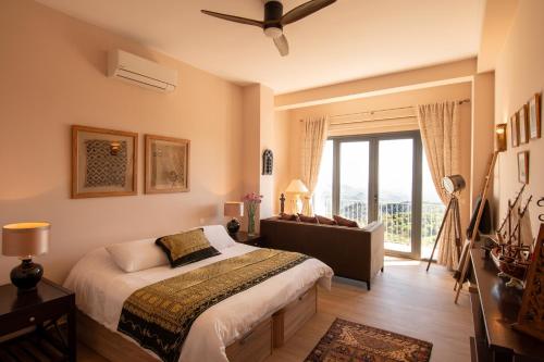 a bedroom with a bed and a couch and a window at CASA EMILIANA The Town-House Gaucin Spain in Gaucín