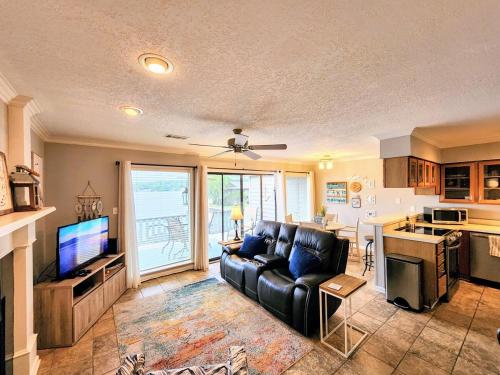 a living room with a black leather couch and a kitchen at Farr Shores Cozy Retreat in Red Oak